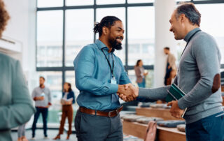 Happy businessmen greeting while attending an education event at conference hall.